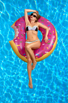 Woman in bikini on the inflatable mattress in the swimming pool.