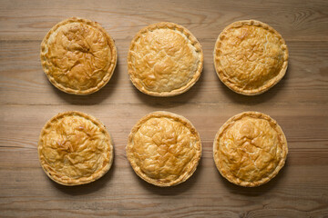 Overhead of Six Cooked Whole Pies on Wooden Surface