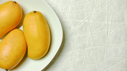 Naklejka na ściany i meble Mangoes in white bowl on white textured paper 
