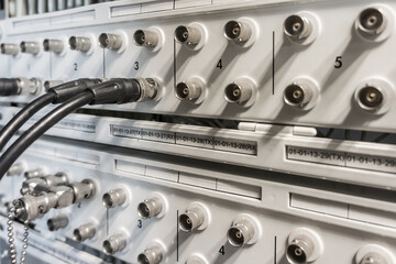 Coaxial cable plugged into BNC interface port of communication equipment. Transmission system in telecommunication room.