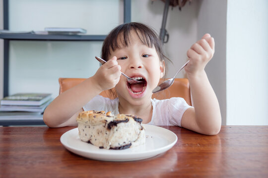 Little Asian Girl Eating Bread With Chocolate At Home