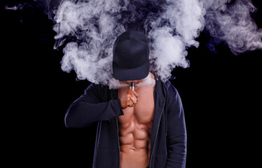 A young guy with a sports figure Smoking e -  cigarette. (vape)