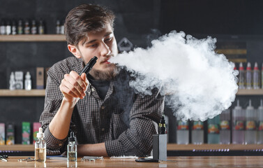 Vape. Vaping man in a cloud of vapor. Photo is taken in a vape bar ( shop ).