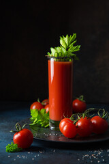 glass of tomato juice served with  cucumber and celery