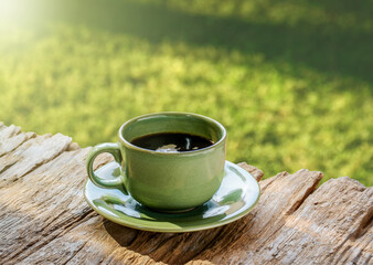 Coffee cup placed on rustic wooden plank with diagonal sunlight in the garden. Afternoon coffee time in the garden.