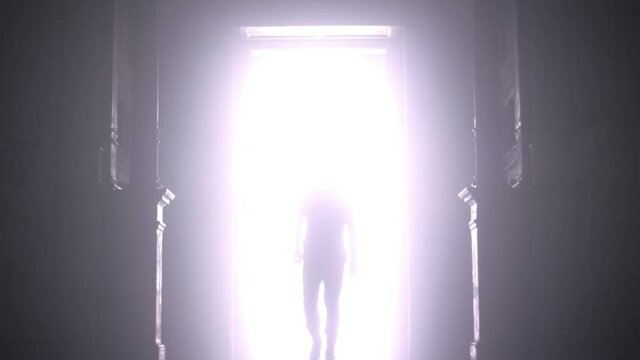Man silhouette walking from light. Door open light. Male silhouette going from light on black. Man open light in dark and go straight. Hope concept. Dream concept