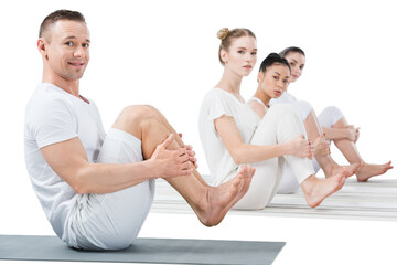  man and women performing boat position on yoga mats isolated on white