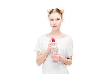 Attractive young woman in white t-shirt holding bottle with water and looking at camera