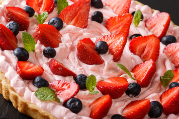 Tart with strawberries and blueberries and a pink delicate cream close-up. horizontal