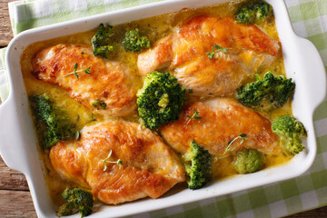 Homemade chicken breast baked with broccoli in cheese sauce close-up in dish. horizontal top view