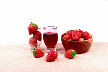 Fresh strawberries and strawberry jam in the glass  jar and strawberries in a wooden bowl