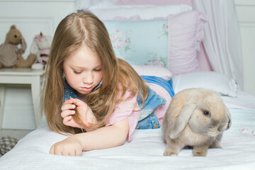 girl with pet rabbit lying on the bed. the concept of Allergy