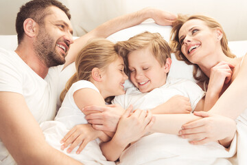 Obraz premium happy smiling caucasian family lying in bed in the morning