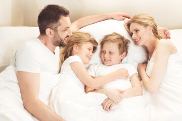 Obraz premium happy smiling caucasian family lying in bed in the morning