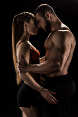 young sensual sporty couple embracing isolated on black