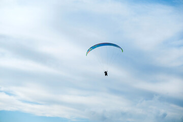 Paragliders in bright blue sky, tandem of instructor and beginner