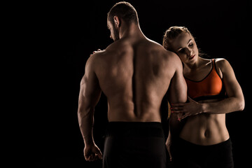 Fototapeta na wymiar young caucasian sporty couple embracing isolated on black