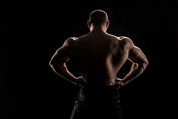 Fototapeta premium back view of young shirtless athlete flexing back muscles