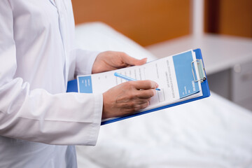 partial view of doctor writing diagnosis in clipboard at hospital