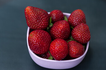 Strawberries in a bowl on grey background, top view