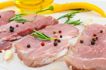 Raw flat meat for steak (chop) with spices on a light background.