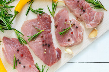 Raw flat meat for steak (chop) with spices on a light background.