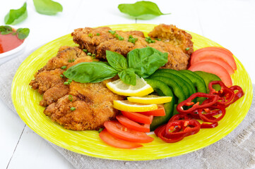 Schnitzel with vegetables, tomato sauce on a white wooden background.