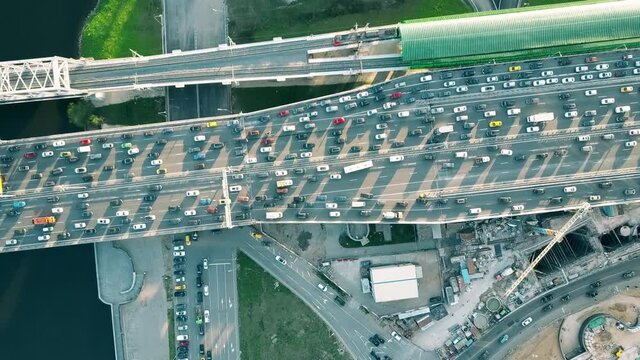 Aerial Top Down Shot Of Heavy Congested Road Traffic And Moving Commuter Train In The Rush Hour. Private Cars Versus Public Transport Concept. 4K Video