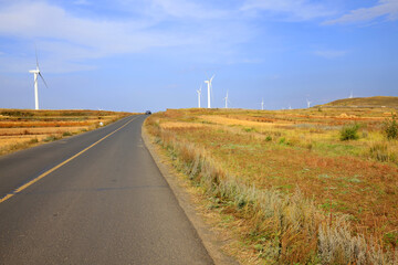 Fototapeta na wymiar Asphalt road and wind turbines