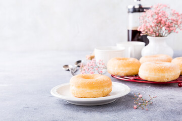Doughnuts with powdered sugar and cups of coffee on light gray background. Selective focus. Copy space.