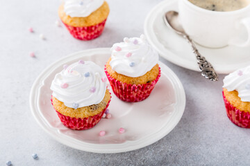 Mini cupcakes with white frosting cream and pink sprinkles on light gray background. Birthday party food concept.