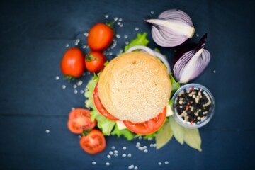 Hamburger with cheese, meat, tomatoes and onions and herbs. On Wooden background. Top view. Free space.
