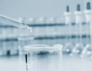 Laboratory closeup of droper with Beaker on science glassware background .