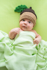 Baby with a knitted hat on back. Newborn boy lying on a bed in the cap