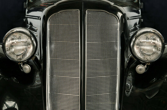 Front headlights and grille of a restored vintage car and hood ornament, close up frontal. Vintage