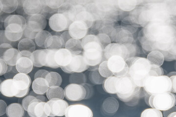 Water bokeh background. Defocused water surface with waves glittering in the sun