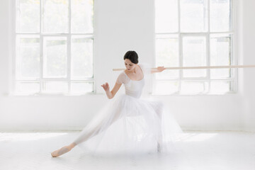 Young and incredibly beautiful ballerina is posing and dancing in a white studio