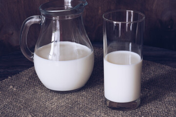 Milk in a glass and jug on a wooden table.
