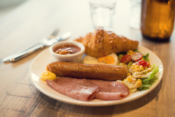 English breakfast with fried eggs, bacon, sausages, beans, toasts and fresh salad
