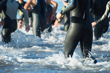 Triathletes running out of the water on triathlon race - obrazy, fototapety, plakaty