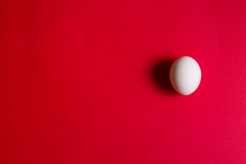 Top view of white egg on the red background