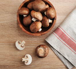 Fresh brown chestnut mushrooms whole in wooden plate
