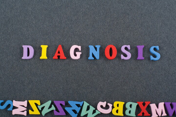 DIAGNOSIS word on black board background composed from colorful abc alphabet block wooden letters, copy space for ad text. Learning english concept.