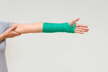 Injury woman wearing sports ware with green cast on hand and arm, body injury concept