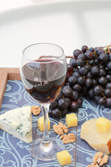 Red wine and grapes with cheese on wooden table