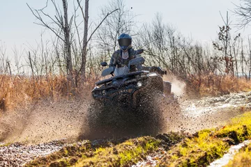 Fotobehang ATV racer drives through mud and water © yo camon
