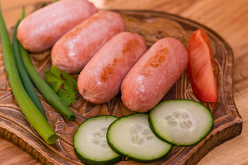 Breakfast of fried mini sausages with vegetables on a wooden stand close-up