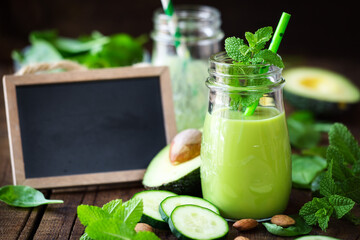Green detox smoothie with avocado, cucumber, spinach and with fresh mint. Healthy eating, weight loss and dieting concept with a blackboard at the backgrond with copy space for your text