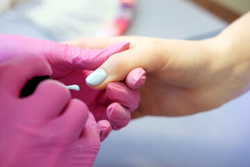 Manicurist painting nails with nail polish