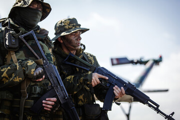 Photos of a group of military men with a gun in front of a helicopter